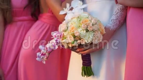 新娘手里拿着一束兰花和玫瑰周围是伴娘视频的预览图