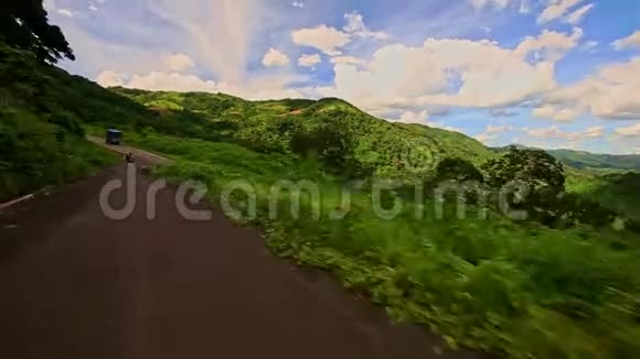 沿着弯曲乡村道路在绿色丘陵景观中的运动视频的预览图