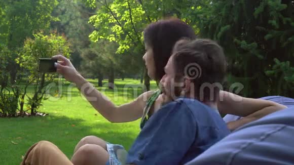 年轻夫妇坐在公园的搁脚凳上自拍视频的预览图