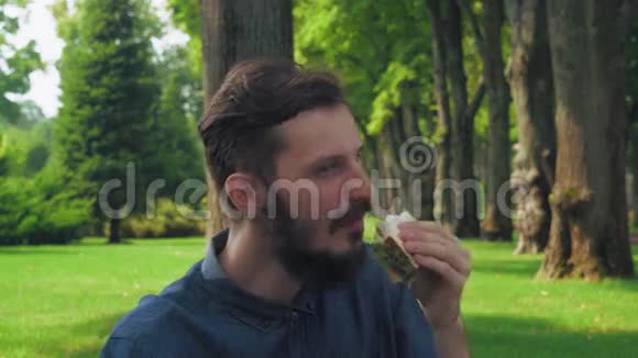 男人在公园里吃一个三明治和沙拉享受着味道闭上了眼睛视频的预览图