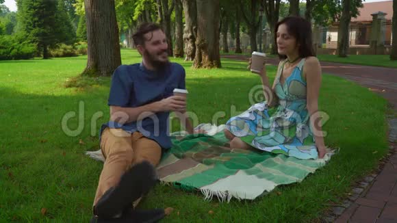 一个男孩和女孩在公园的草坪上聊天喝咖啡视频的预览图