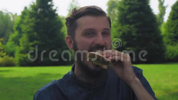 一个年轻人在公园里吃三明治和沙拉视频的预览图