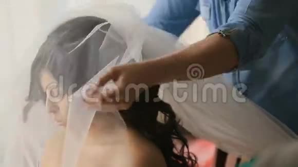 化妆师在新娘的发型上贴上面纱准备举行婚礼视频的预览图