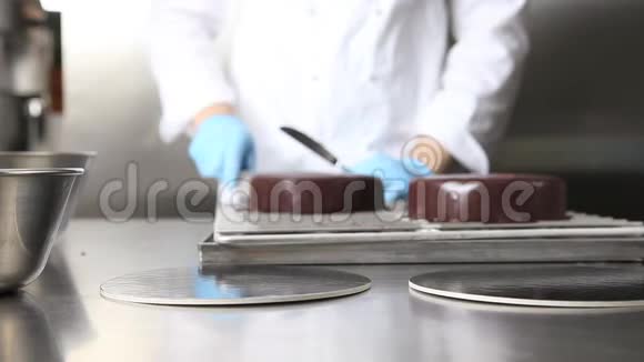 双手糕点厨师准备蛋糕盖上巧克力糖霜在不锈钢工业厨房工作视频的预览图