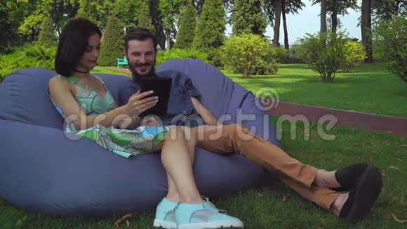 那个带着女孩的家伙坐在椅子上脚凳上浏览平板电脑视频的预览图