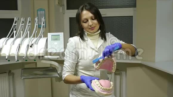 带手套的女牙科医生在下巴模型上展示如何用牙刷正确清洁牙齿视频的预览图