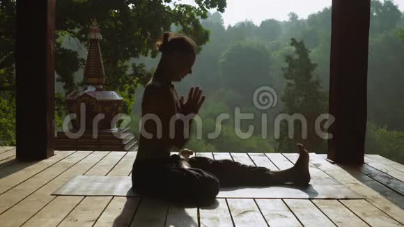 瑜伽坐在半个莲花的位置倾斜到另一个伸出的腿视频的预览图