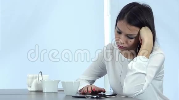 又累又无聊的女孩在咖啡馆里用平板电脑喝咖啡视频的预览图