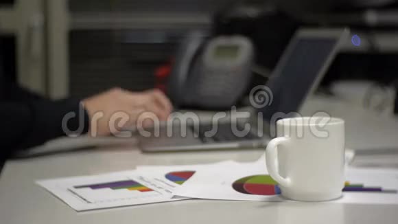一个人从杯子里喝酒在笔记本电脑上打字视频的预览图