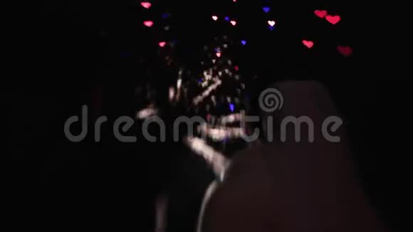 背面剪影婚礼夫妇看着夜空中的烟火以五颜六色的心的形式视频的预览图