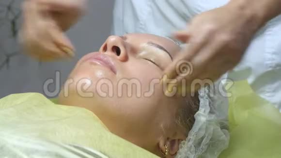 美容师双手抚摸客户的脸面部按摩美女一位美女的肖像视频的预览图