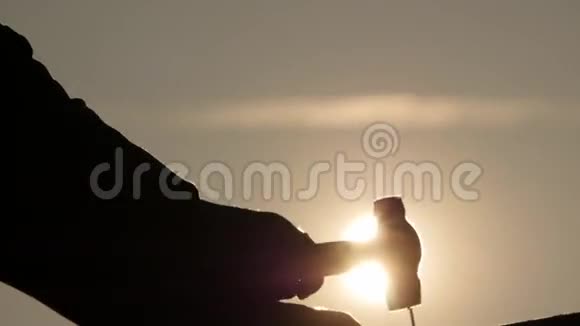 男人的手剪影开始锤钉缓慢的运动与明亮的阳光傍晚视频的预览图