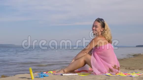 美丽的女人正在海滩上休息看着大海视频的预览图