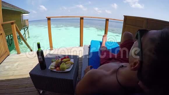 年轻人带着异国情调的饮料坐在露台上马尔代夫度假村视频的预览图