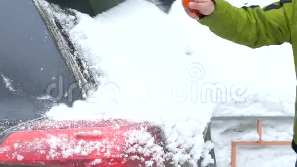 大雪过后人们从汽车挡风玻璃上擦雪视频的预览图