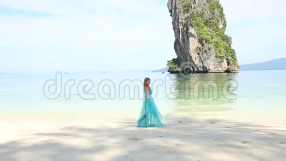 金发女孩站在海滩上与宁静透明的蔚蓝海视频的预览图