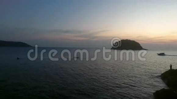空中无人驾驶飞机在平静的水面上飞行靠近野生岛屿游艇在夕阳下行驶柔软的光线视频的预览图
