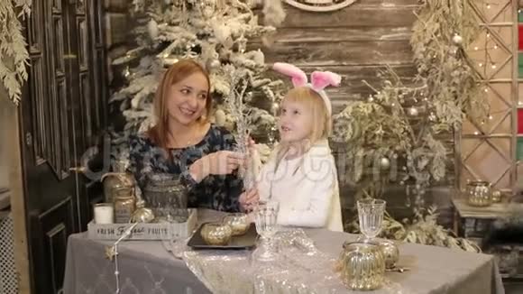母亲和女儿穿着兔子的白色服装靠近圣诞树视频的预览图
