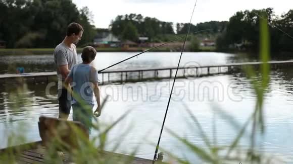 积极的爸爸和儿子在池塘钓鱼视频的预览图