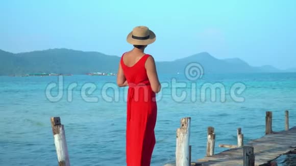 穿着红色长裙的女人这位穿红色衣服的年轻女子在码头上花钱远远地看着女人在码头上花钱视频的预览图