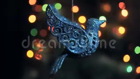 一个闪闪发光的圣诞装饰为一棵圣诞树的形状一只鸟在花环的灯光下旋转视频的预览图
