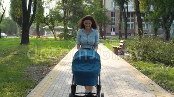 妈妈带着婴儿车在公园里散步夏季自然背景视频的预览图