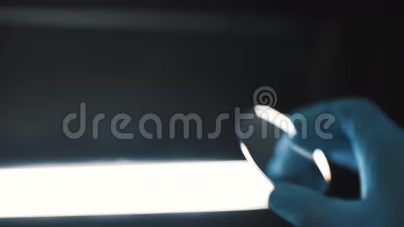 科学家戴上橡胶手套检查圆形玻璃不受光线照射视频的预览图