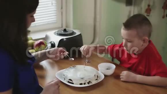 母亲和儿子把巧克力放在蛋糕的顶部视频的预览图