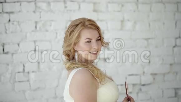 可爱的金发女郎穿着婚纱在工作室里摆着糖果视频的预览图