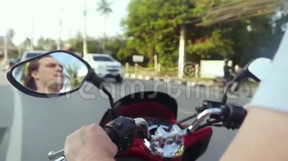 摩托车手驾驶摩托车在柏油路上行驶在美丽的日落时分在热带岛屿上慢动作视频的预览图