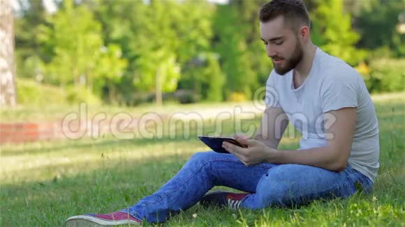 坐在草地上用平板电脑的男孩视频的预览图