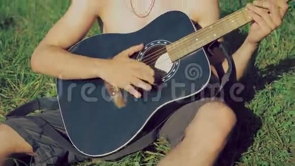 戴着太阳镜和帽子的吉他手在大自然中弹吉他4k视频的预览图