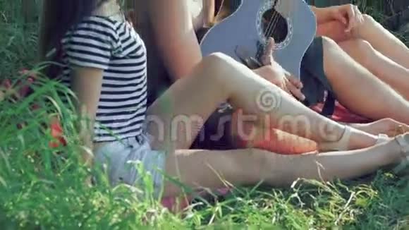 两个女孩和有趣的男孩躺在草地上弹吉他视频的预览图