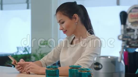 年轻女子在柜台边等咖啡时用电话视频的预览图