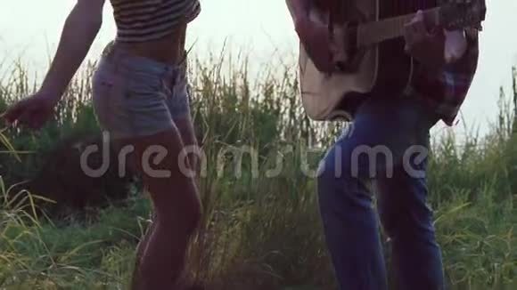 当男孩在湖边弹吉他时年轻女孩跳舞慢慢地视频的预览图