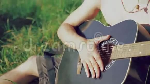 戴着太阳镜和帽子的小男孩在大自然中弹吉他4k视频的预览图