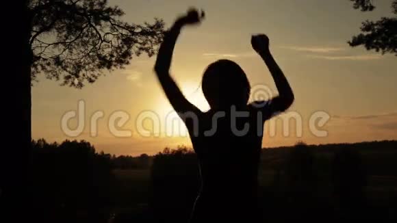 日落时分年轻快乐的女人在森林里跳跃跳舞和玩耍视频的预览图