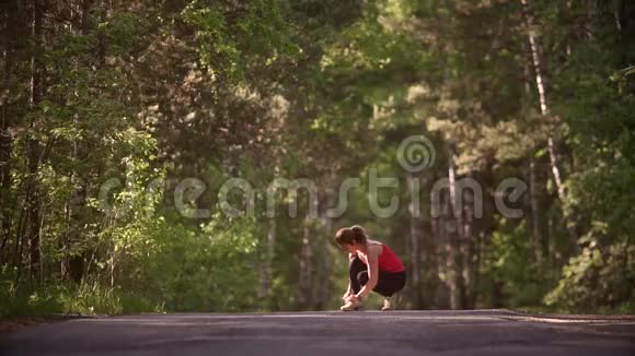 年轻女子系好运动鞋准备慢跑一个戴着智能手表的女孩正在夏天的森林里做运动视频的预览图