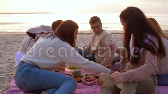 快乐的朋友在海滩野餐时吃三明治视频的预览图