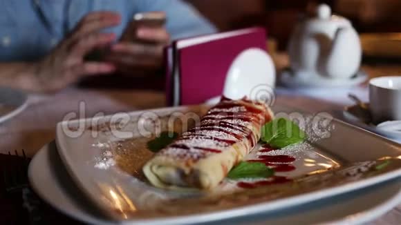 盘子里有草莓煎饼背景上有电话的人视频的预览图