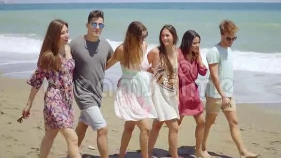 时髦的年轻朋友光着脚在海滩上散步视频的预览图