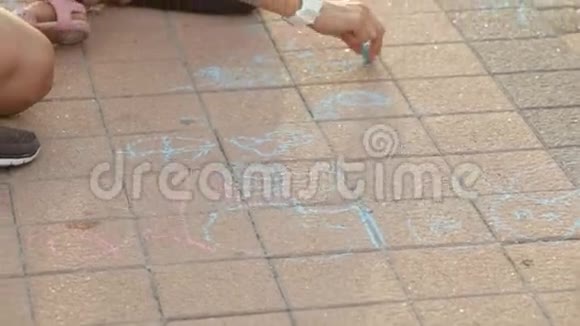 可爱的女孩和她的母亲在人行道上用粉笔画画视频的预览图