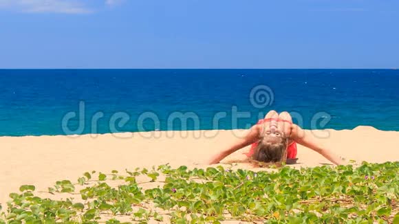 红色的金发女孩躺在前景的绿色的沙滩上视频的预览图
