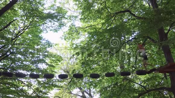 一个人走在一个绳索公园的悬索小路上视频的预览图