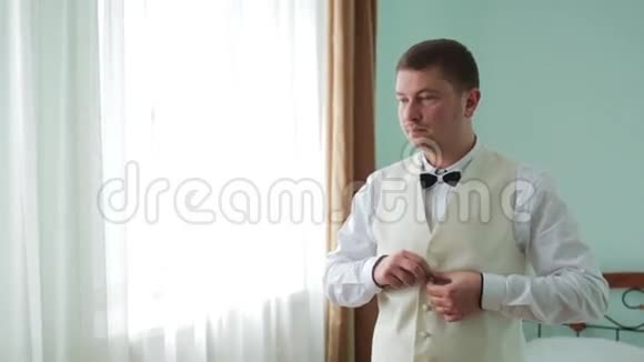 年轻的新娘礼服和衬衫纽扣新婚快乐的年轻新郎男人把衬衫扣在窗前视频的预览图