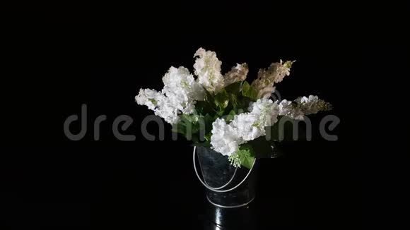 白色花瓶里的丁香花在黑色背景上旋转视频的预览图