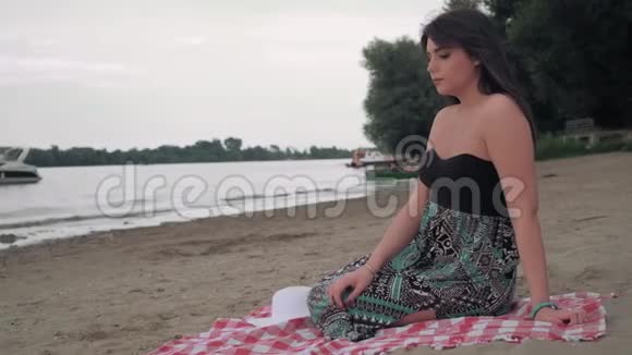 悲伤的女孩坐在沙滩上思考视频的预览图