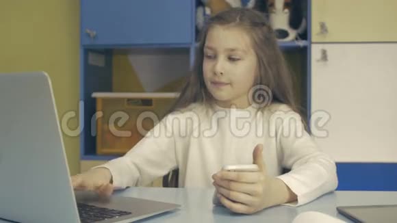 聪明的孩子小女生坐在办公桌前用笔记本电脑视频的预览图