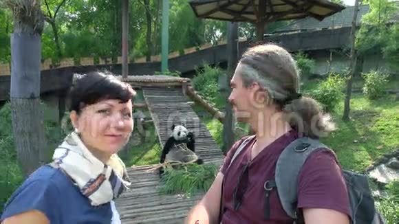 两个快乐的人在动物园里看熊猫视频的预览图