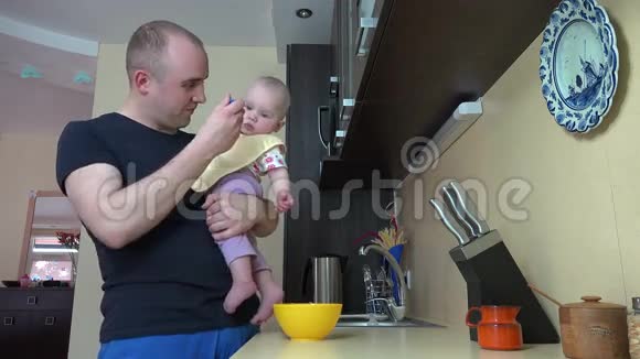 快乐的父亲在厨房用勺子喂婴儿4K视频的预览图